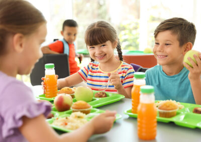 Kinder sitzen am Tische und essen.