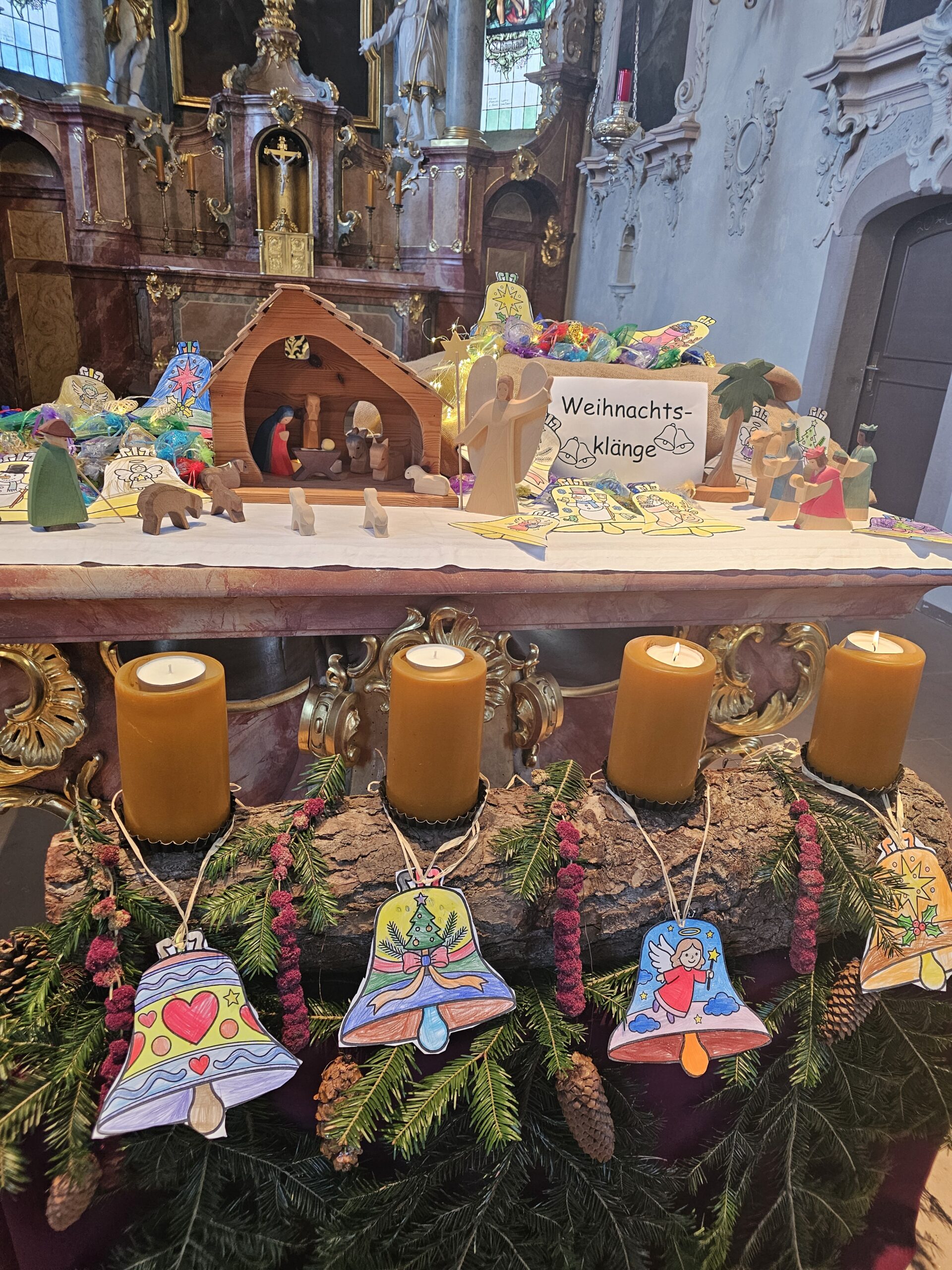 Kirche mit Weihnachtsgrippe und 4 Kerzen im Vordergrund.