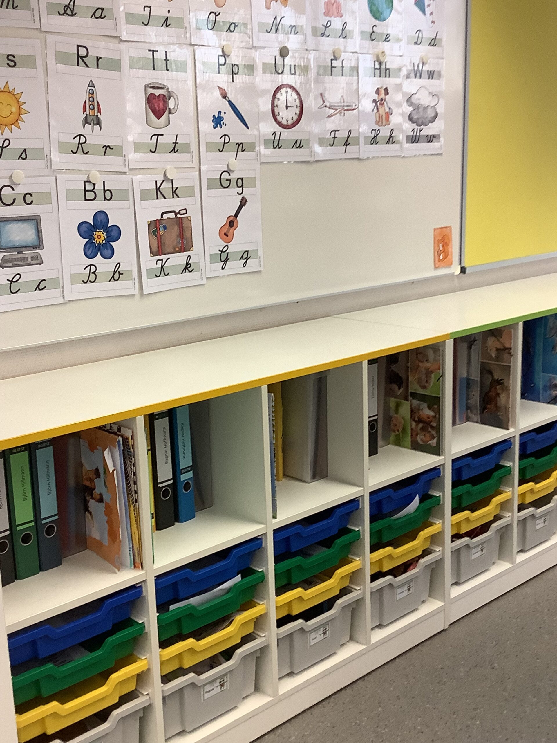 Regale mit Ordnern und Schubladen im Klassenzimmer.