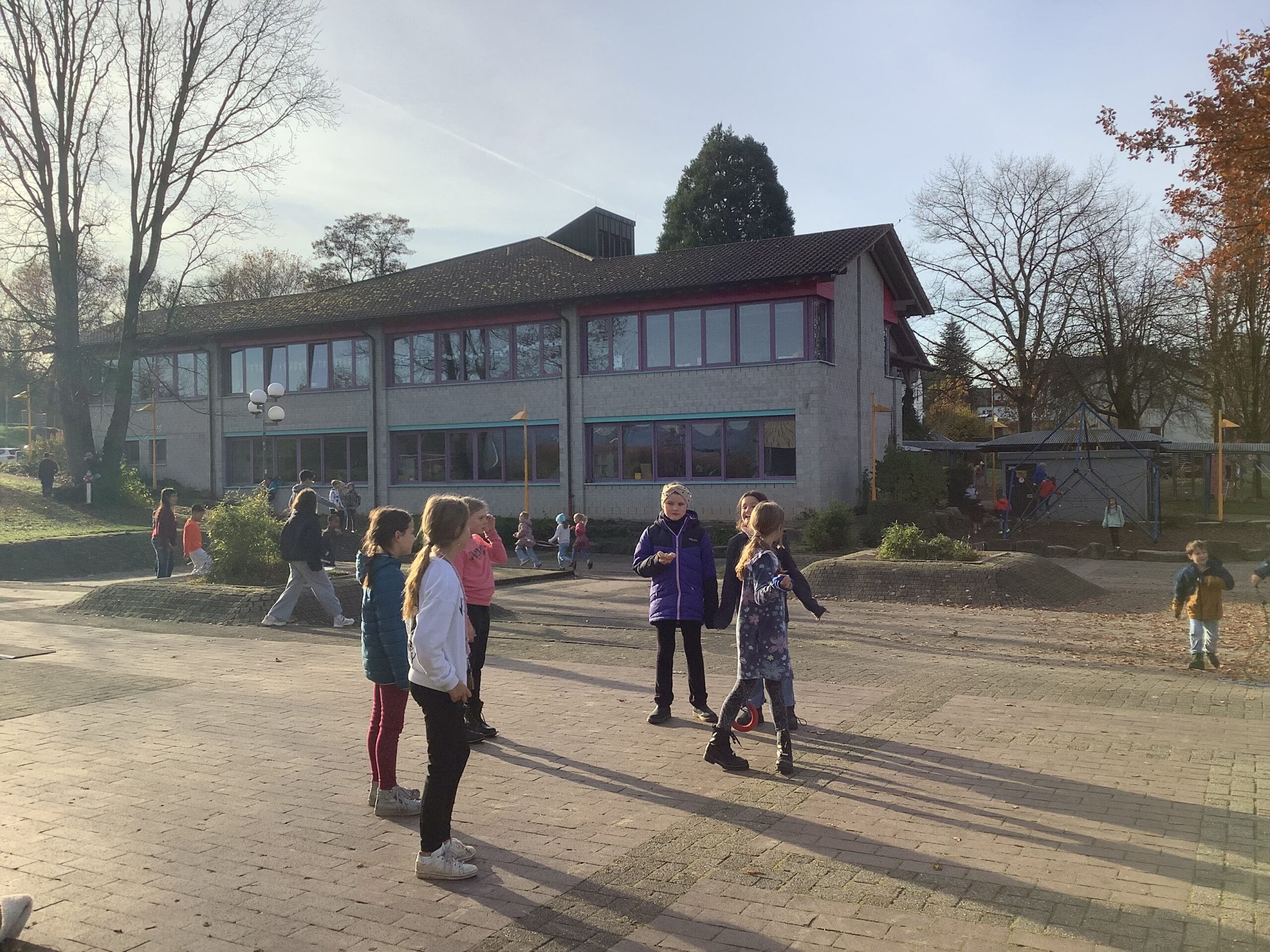 Schulhof mit spielenden Kindern im Herbst.