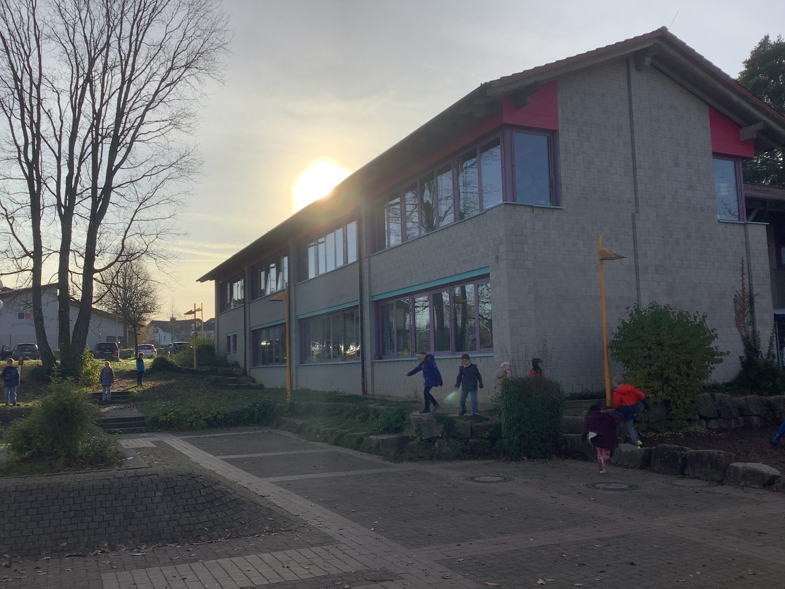 Schulhof mit spielenden Kindern im Herbst.
