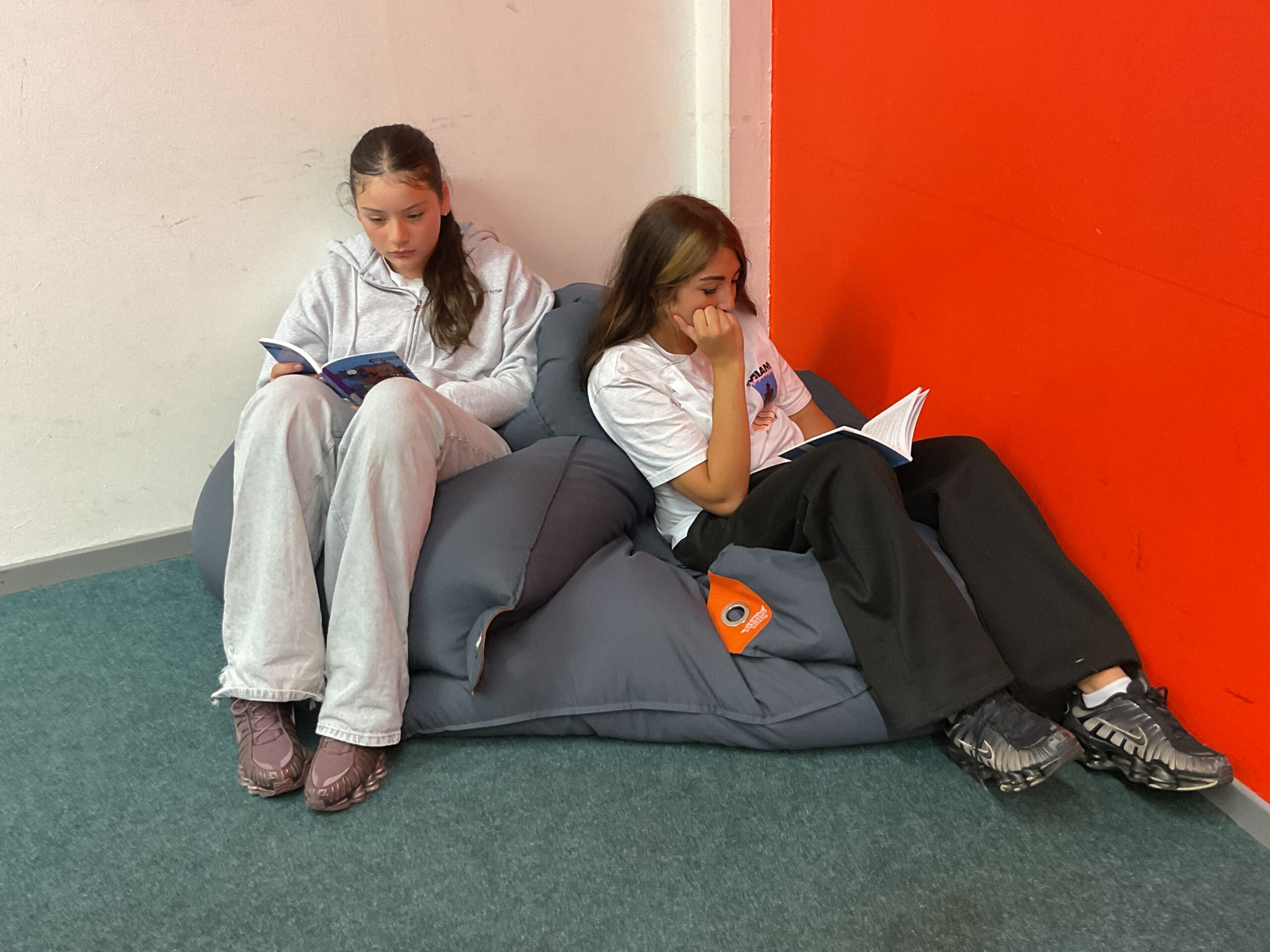 Zwei Schülerinnen sitzen auf Sitzsäcken und lesen.