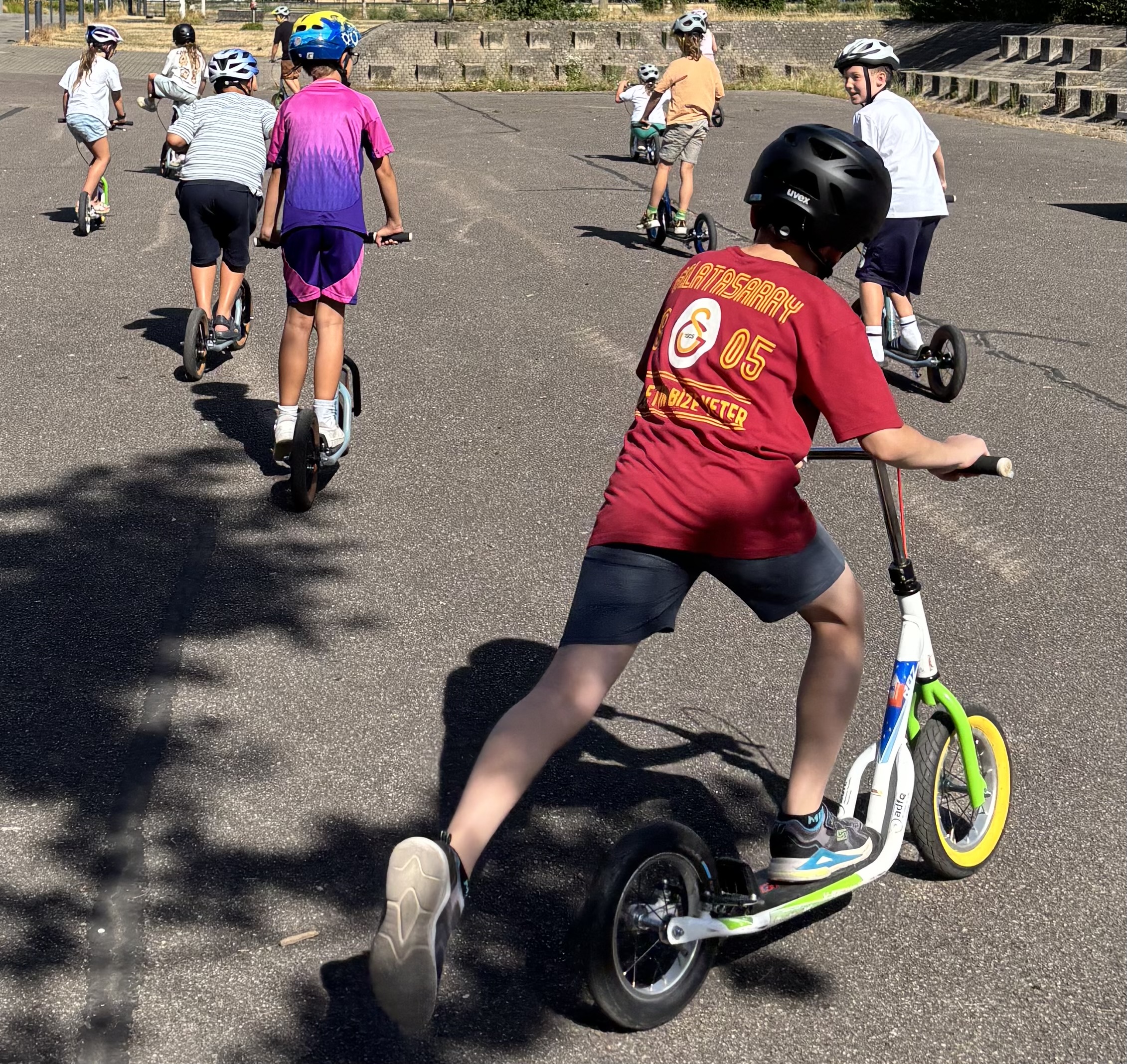 Kinder fahren im Schulhof Roller.